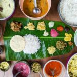 traditional south indian food platter with rice and other variety food items served in a banana leaf for a festival or occasion